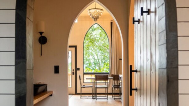 Ein Korridor mit Gewölbedecke, einem großen Bogenfenster und einer Chandelier.