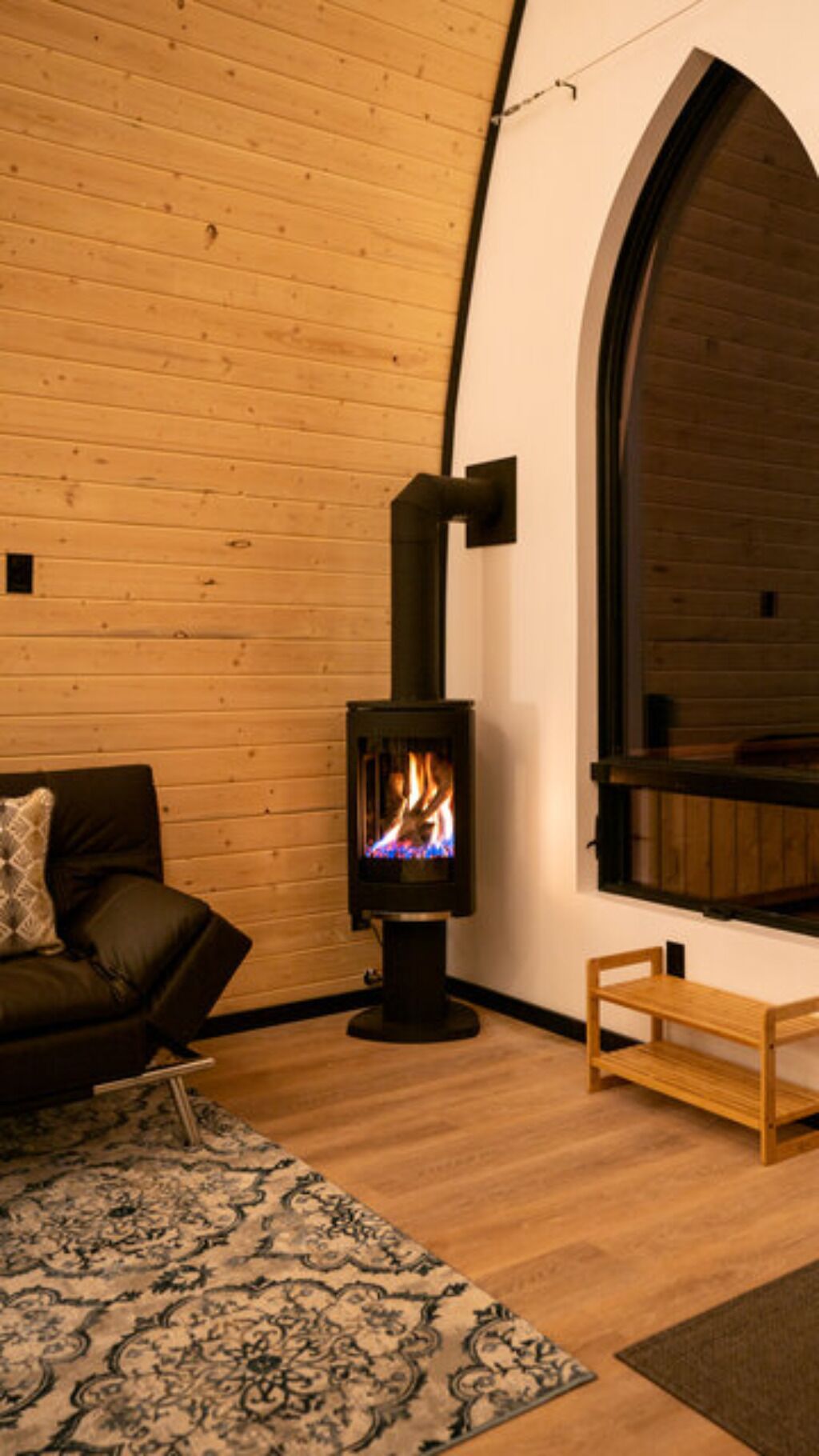Une pièce chaleureuse avec un plancher en bois, un canapé, une petite table en bois et un poêle à bois.