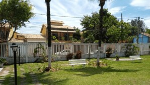 A courtyard with a paved walkway, benches, and a fence. - Cabo Frio Parque Burle Aluguel Economico (Cabo Frio)