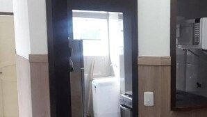 A narrow hallway leading to a kitchen area with a washing machine, a microwave, and a stove. - Cabo Frio Parque Burle Aluguel Economico (Cabo Frio)