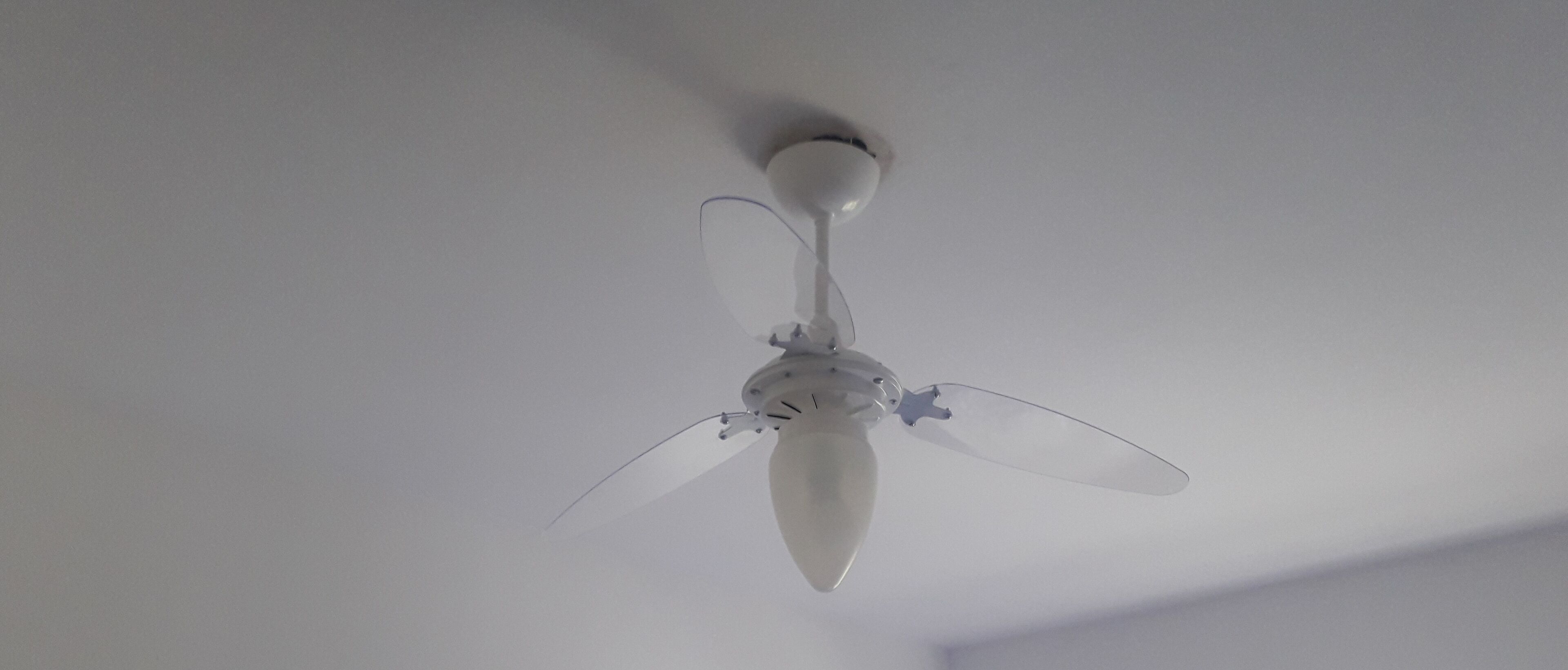 Un ventilador de techo con tres aspas y una lámpara central.