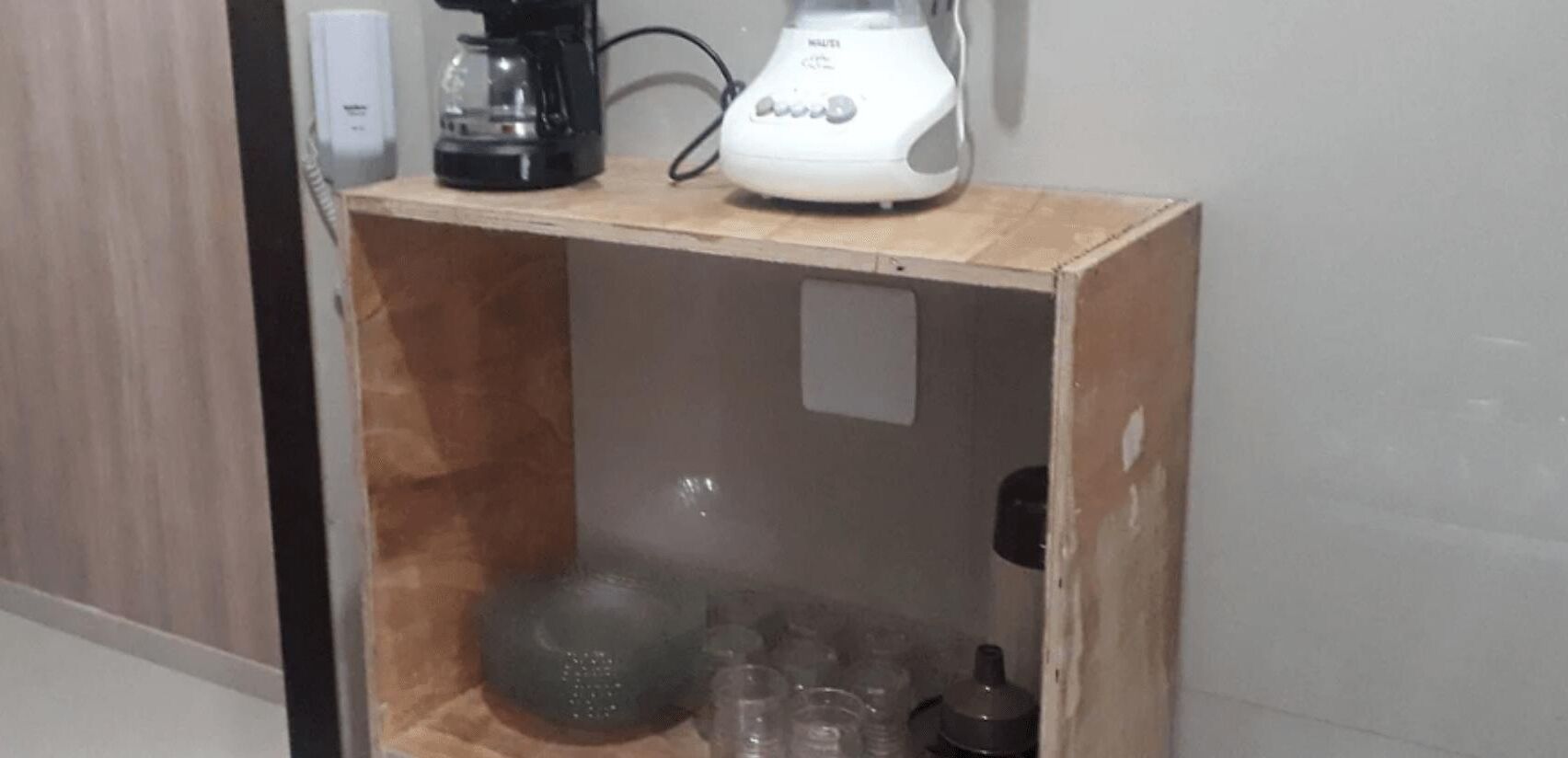 Un mueble de madera con una cafetera y un electrodoméstico blanco encima.