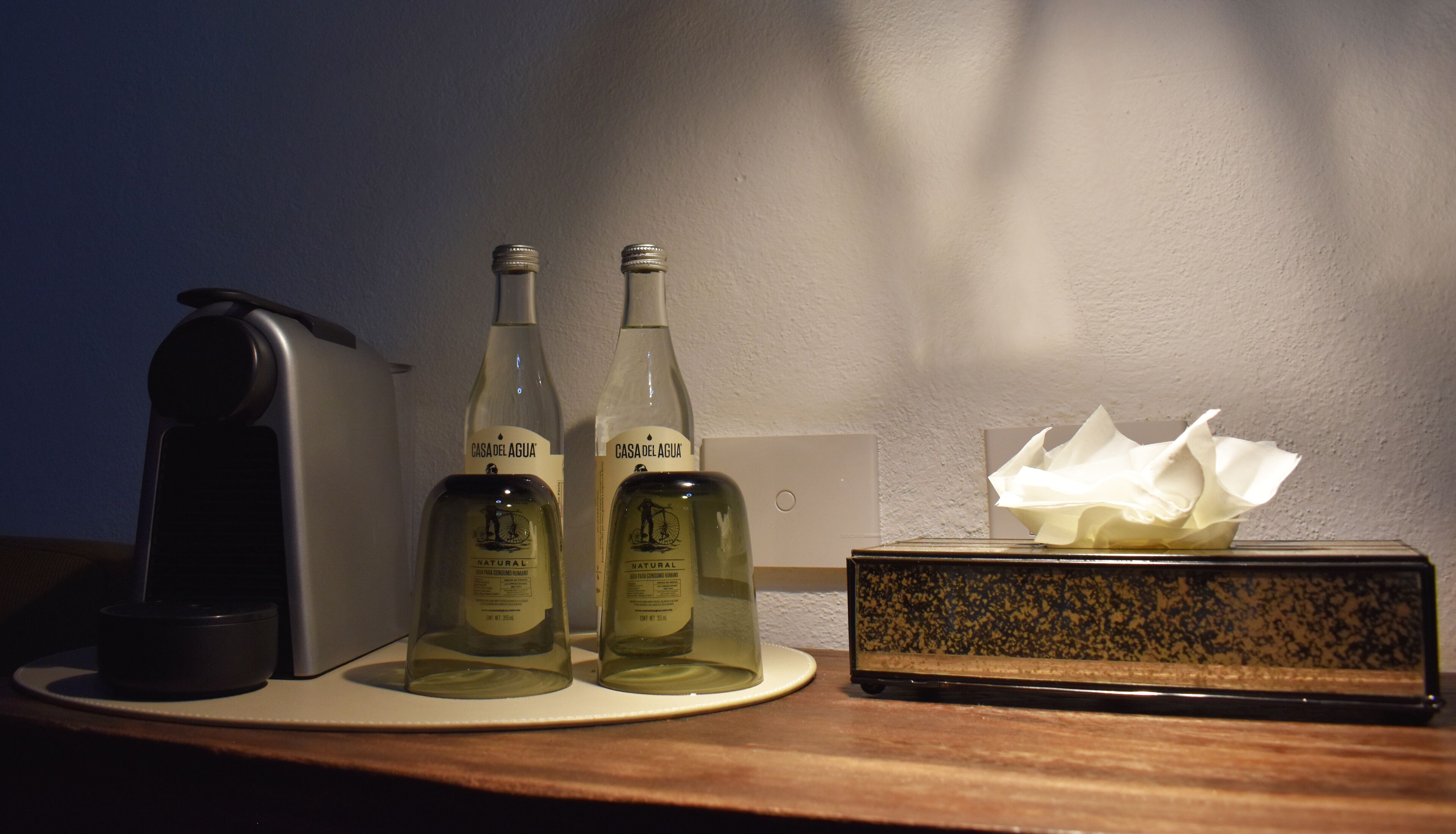 Two bottles of natural wine, a tissue box, and a coffee maker on a table.