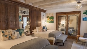 Una habitación con dos camas, una silla y un espejo.