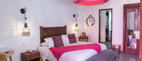 Un dormitorio con cama, mesitas de noche, un escritorio y un banco.