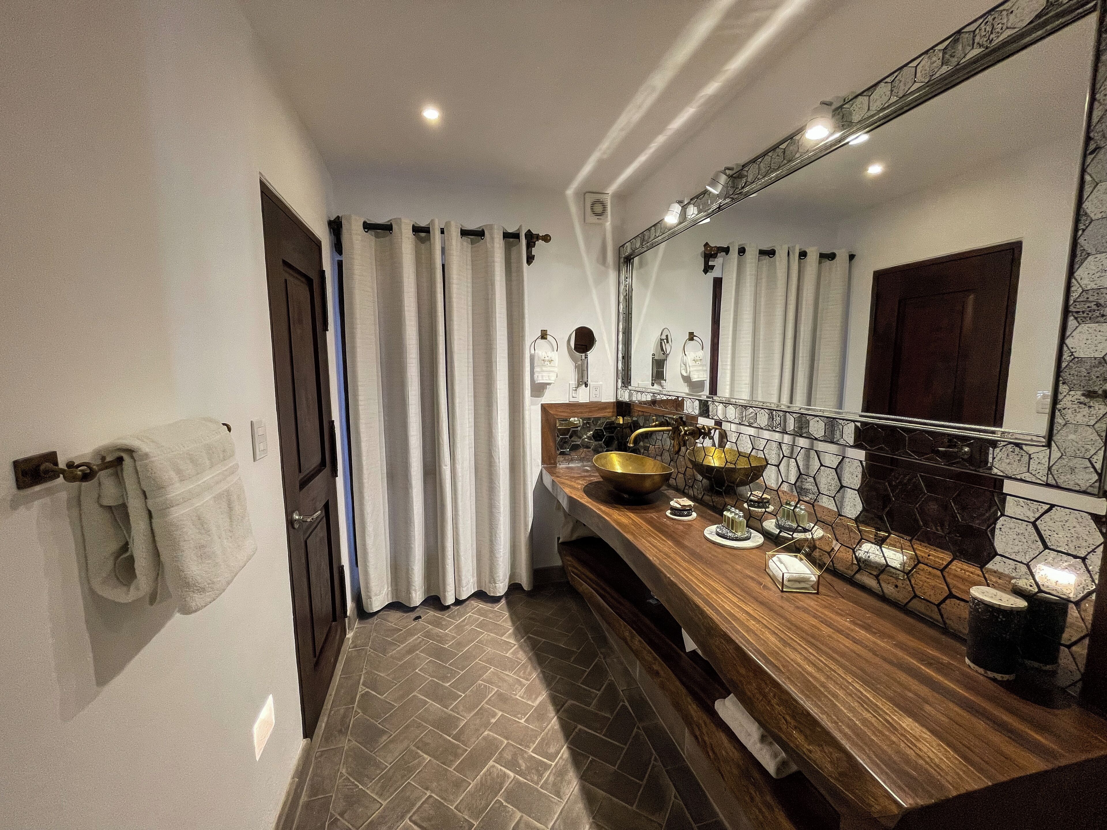 A bathroom with a wooden vanity, a large mirror, and a tiled backsplash.