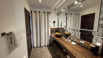 A bathroom with a wooden vanity, a large mirror, and a tiled backsplash.
