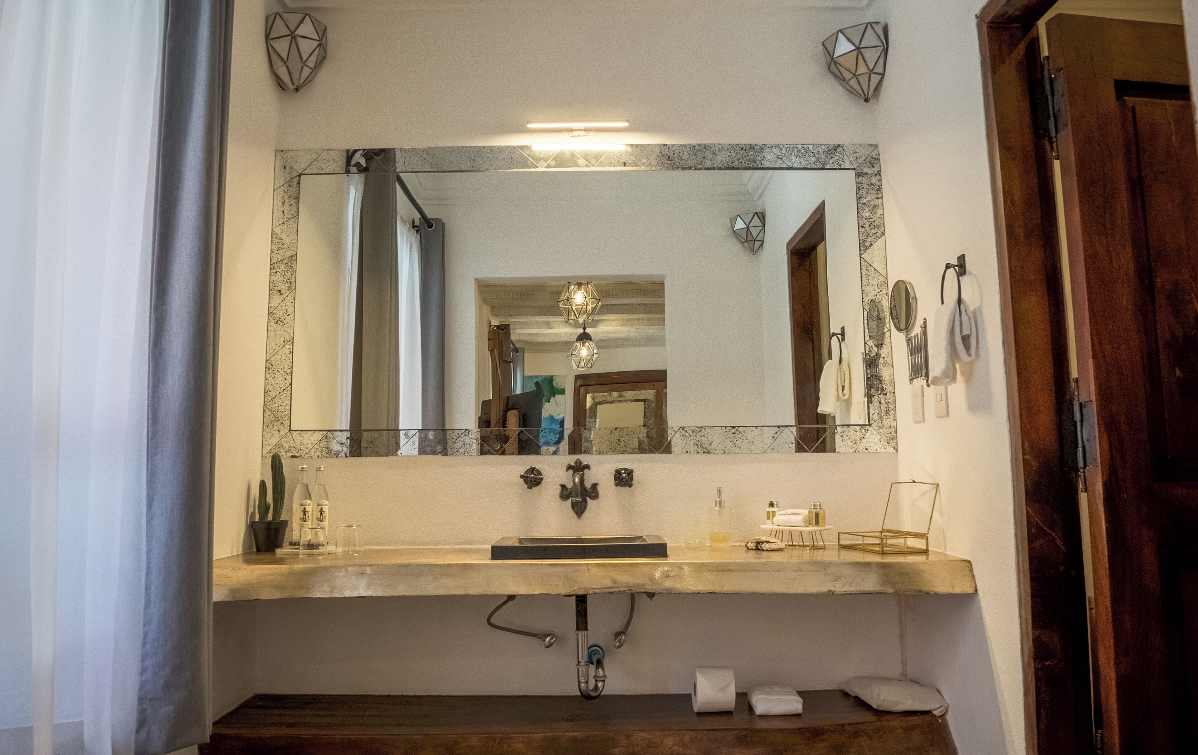 A bathroom with a large mirror, a sink, and a towel rack.