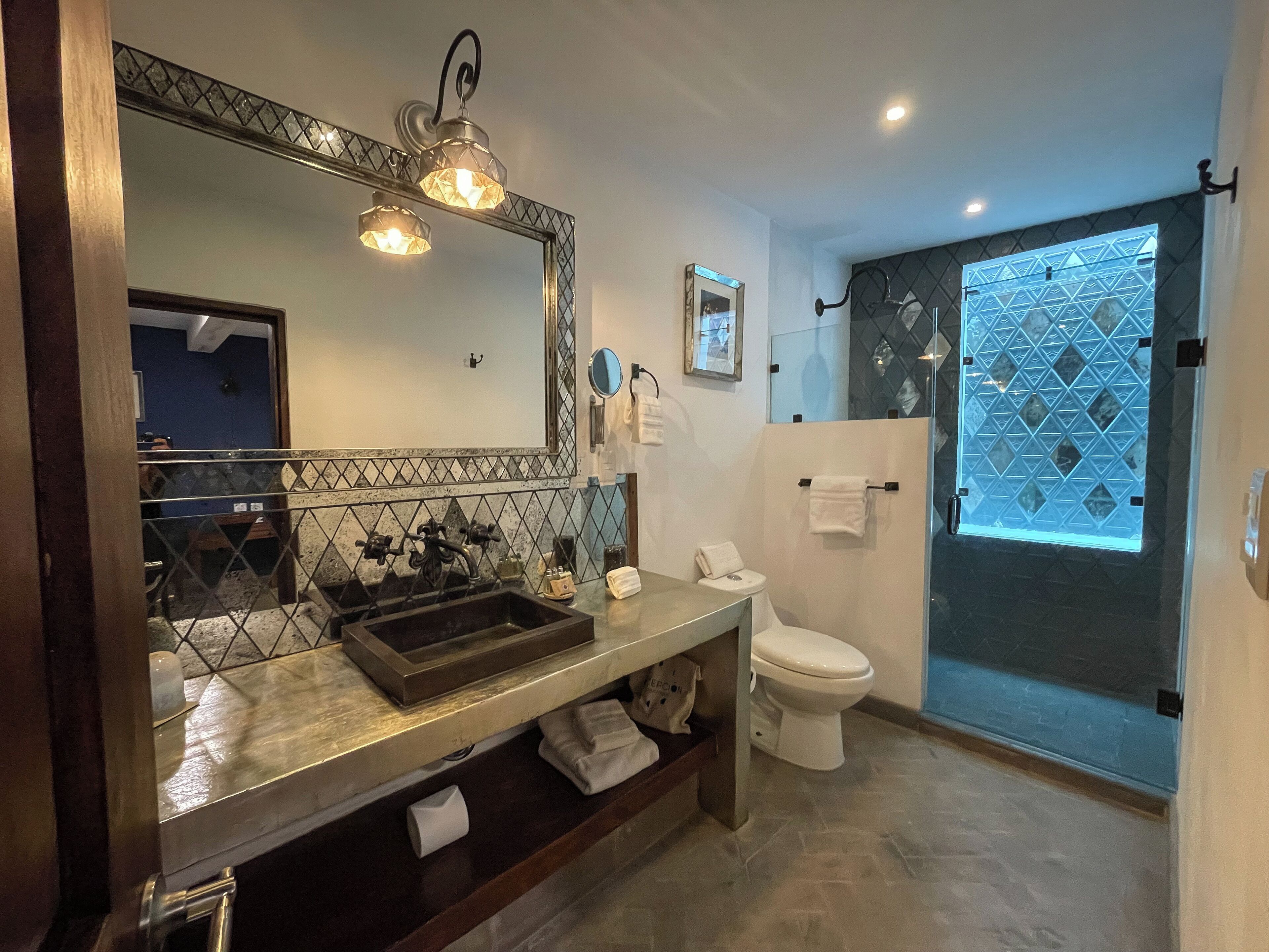 A modern bathroom with a large mirror, a sink, a toilet, and a shower area.