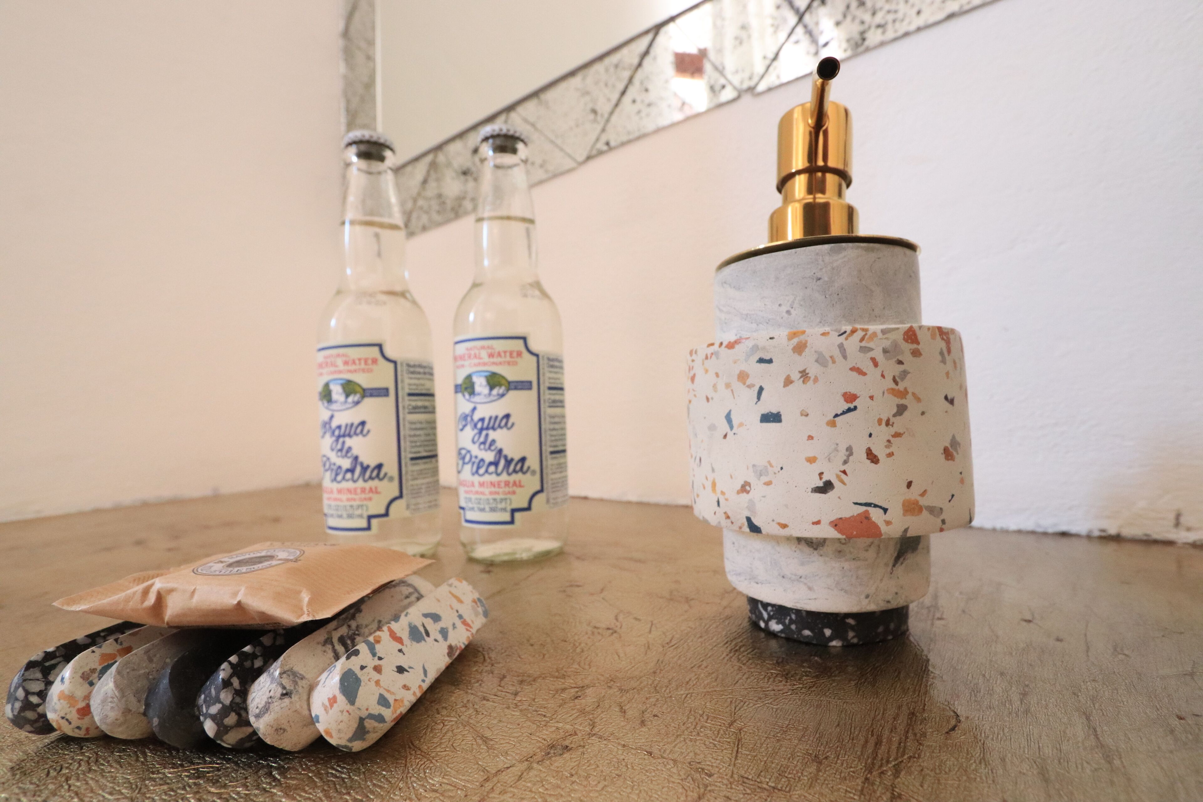 A table with bottles of Agua de Piedra mineral water, a decorative ceramic object, and a package of sausages.