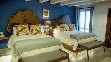 A hotel room with two beds, a wooden headboard, a nightstand with a lamp, and a large window with curtains.