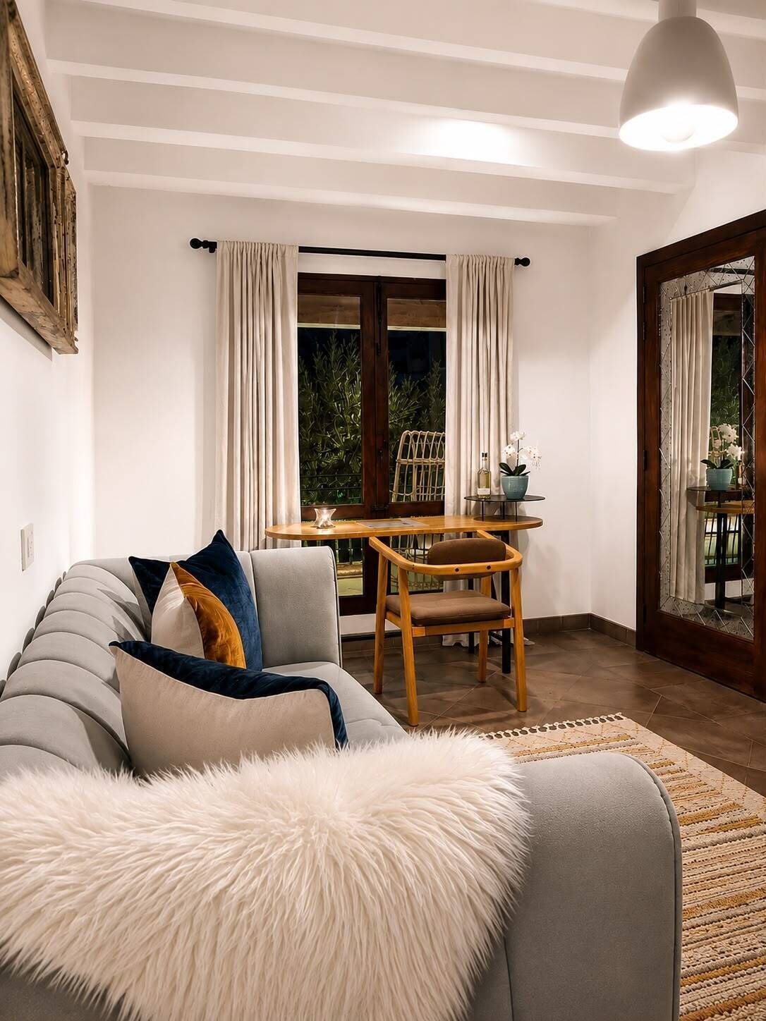 Un salon comprenant un canapé, une table à manger avec des chaises, une fenêtre avec des rideaux et une porte donnant sur l’extérieur.