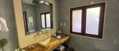 Un baño con un espejo grande, un tocador de madera, un lavabo, un inodoro y una ventana con vidrio esmerilado.