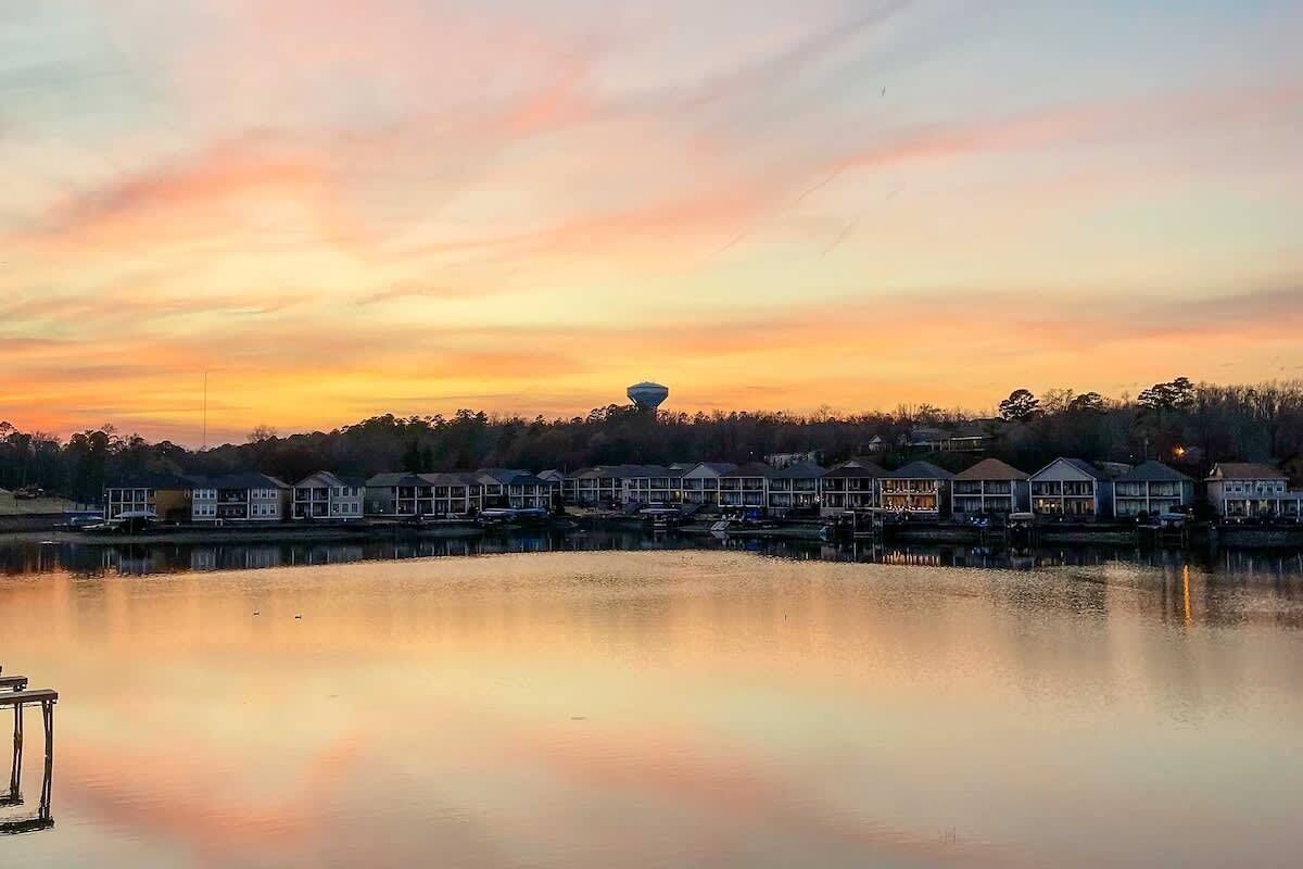 Una propietat al costat del mar amb una filera de cases, un moll i un llac tranquil que reflecteix el cel.