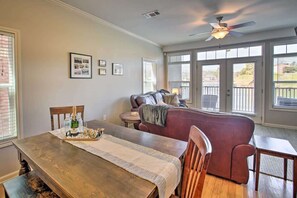 Un espace repas comprenant une table en bois, des chaises, un ventilateur de plafond et une vue dĂ©gagĂ©e grĂące Ă de grandes fenĂȘtres.