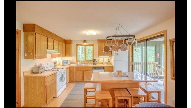 A modern kitchen with wooden cabinets, a central island, and a hanging pot rack. - My Mountainside Mansion in Waterville Estates!🏔☀️🏊‍♀️⛷ (Campton)