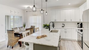Een moderne keuken met witte kasten, een marmeren eiland en hanglampen.