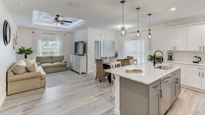 Een moderne keuken met een centraal eiland, witte kastjes en hanglampen.