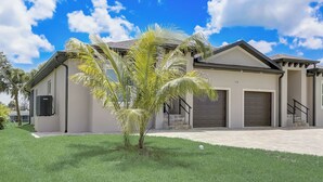 Een modern huis met een verzorgd gazon, een palmboom en een garage.