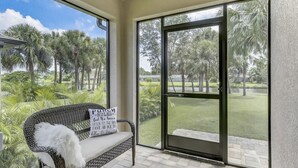 A patio with a wicker bench and a view of a golf course. - WaterFront Boundary vacation! Close to beaches 3bdr2bath,golfing fishing (Rotonda West)