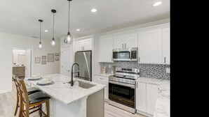 A modern kitchen with white cabinetry, a marble countertop, stainless steel appliances, and pendant lighting. - WaterFront Boundary vacation! Close to beaches 3bdr2bath,golfing fishing (Rotonda West)