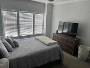 Relax in a serene bedroom with a large bed, flat-screen TV, and dresser.