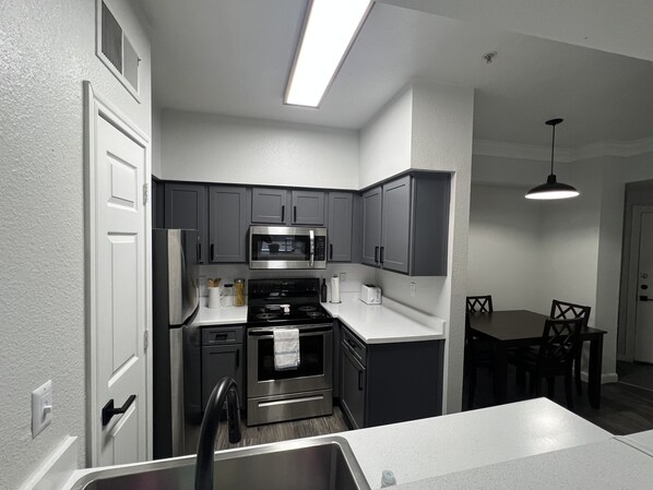 Enjoy meals in the kitchen with a gas stove, microwave, and refrigerator, and dine at the adjacent table with chairs.