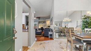 A spacious living area with a dining table and chairs, a sofa, and a chandelier.