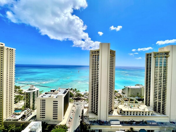 A high-rise hotel with multiple floors, a swimming pool, and a view of the ocean.