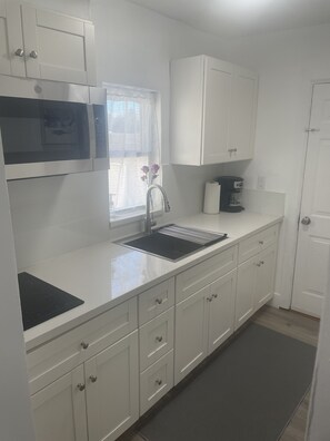 Enjoy cooking in this well-equipped kitchen with a sink, stainless steel range hood, and coffee maker.