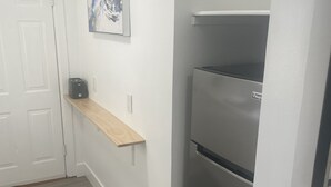 A kitchen with a stainless steel refrigerator, a wooden shelf, and a door. - Remodeled Stand alone Cottage.B (Phoenix)