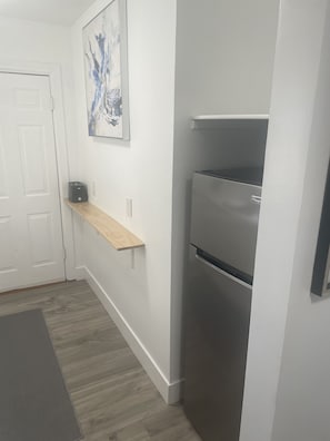 Enjoy cooking in this well-equipped kitchen with a refrigerator, wooden shelf, and ample counter space.