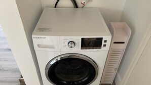 A front-loading washing machine with a control panel, a water inlet, and a hose. - Remodeled Stand alone Cottage.B (Phoenix)