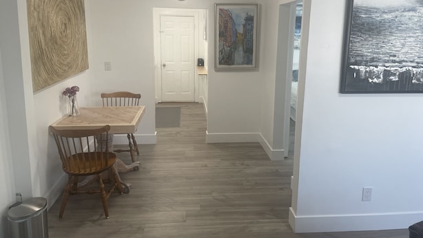 A dining area with a wooden table and chairs, a clock on the wall, and a door leading to another room. - Remodeled Stand alone Cottage.B (Phoenix)