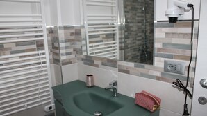 Ein Badezimmer mit einem grünen Waschbecken, einem Spiegel, einem Handtuch und einer Steckdose.