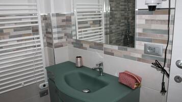 Un bagno con un lavandino verde, uno specchio, un asciugamano e una presa di corrente.