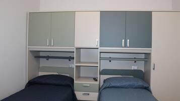 Una camera da letto con due letti singoli, un armadio con scomparti multipli e una libreria.