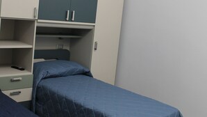 Ein Schlafzimmer mit zwei Einzelbetten, einem Kleiderschrank und einem Schreibtisch.
