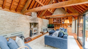 A cozy living room with a stone fireplace, a television, and a sofa. - Barns Lee, Eastcourt - sleeps 9 guests in 5 bedrooms (Eastcourt)