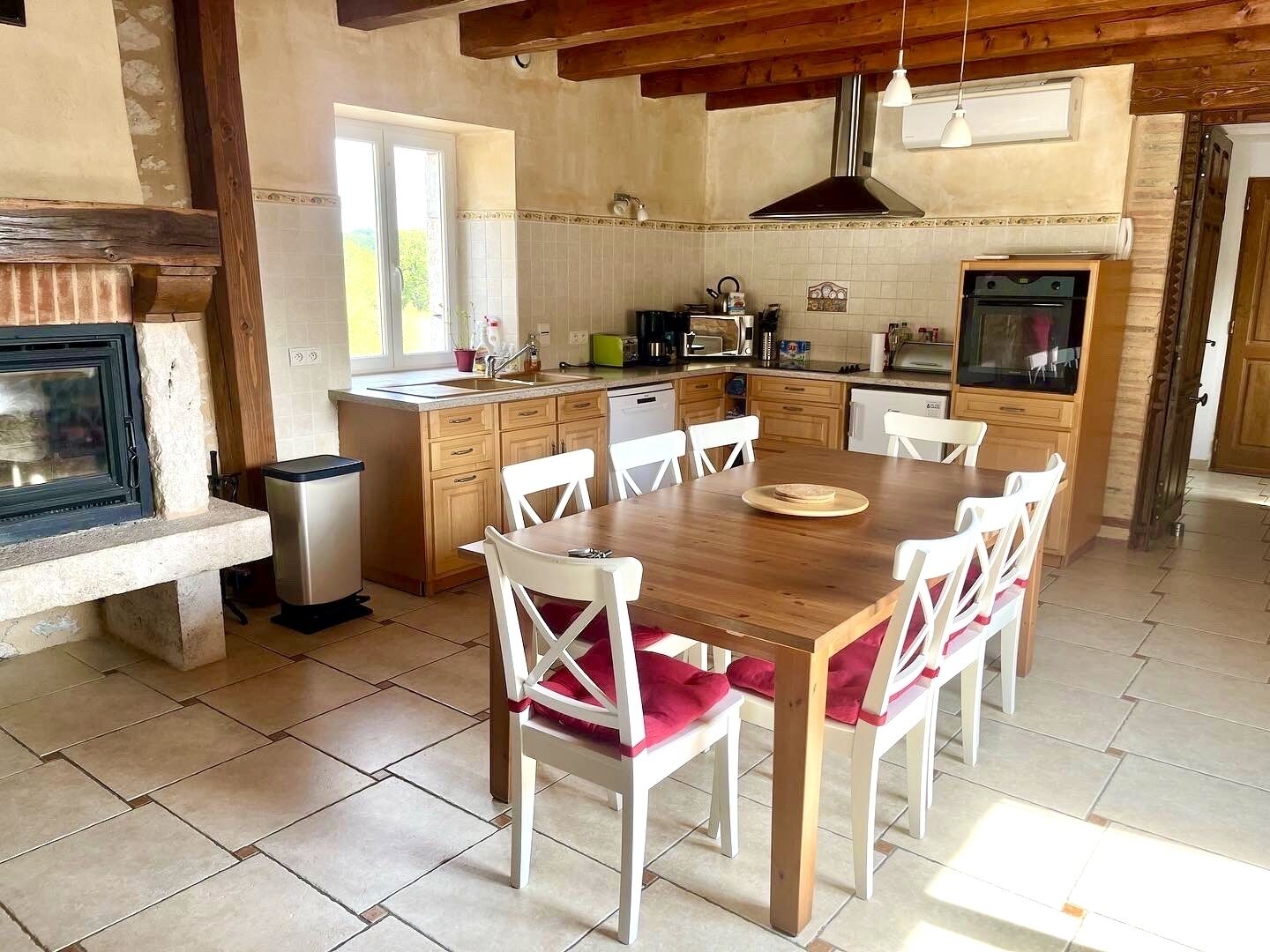 A kitchen with a wooden table, white chairs, and a built-in oven.