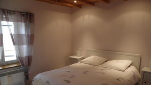 Een slaapkamer met een bed, nachtkastjes, een raam met gordijnen en een radiator.