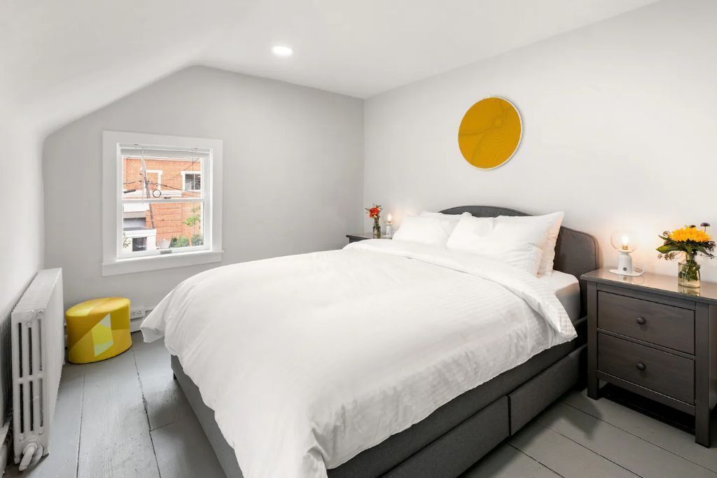 Un dormitorio con cama, mesita de noche y ventana.