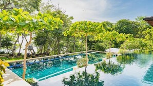 A swimming pool with clear blue water, surrounded by lush greenery and trees.