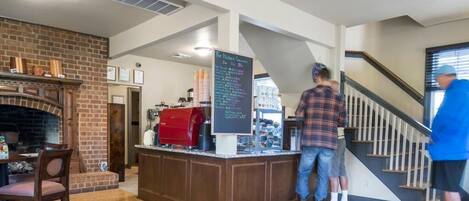 Un restaurante con chimenea de ladrillo, una barra de café y una escalera.