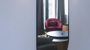 A room with a large oval mirror, two wall-mounted chandeliers, a red chair, and a round table. - H41 Luxury Suites (Belgrade)