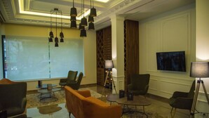 A lobby with a modern design, featuring a large screen, multiple seating areas, and a chandelier. - H41 Luxury Suites (Belgrade)