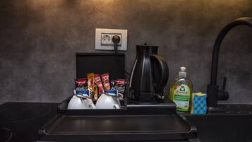 A kitchen counter with a coffee maker, tea pots, and coffee pods.