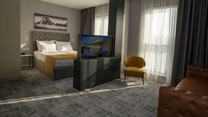 A hotel room with a bed, a TV, a sofa, and a chair. - H41 Luxury Suites (Belgrade)