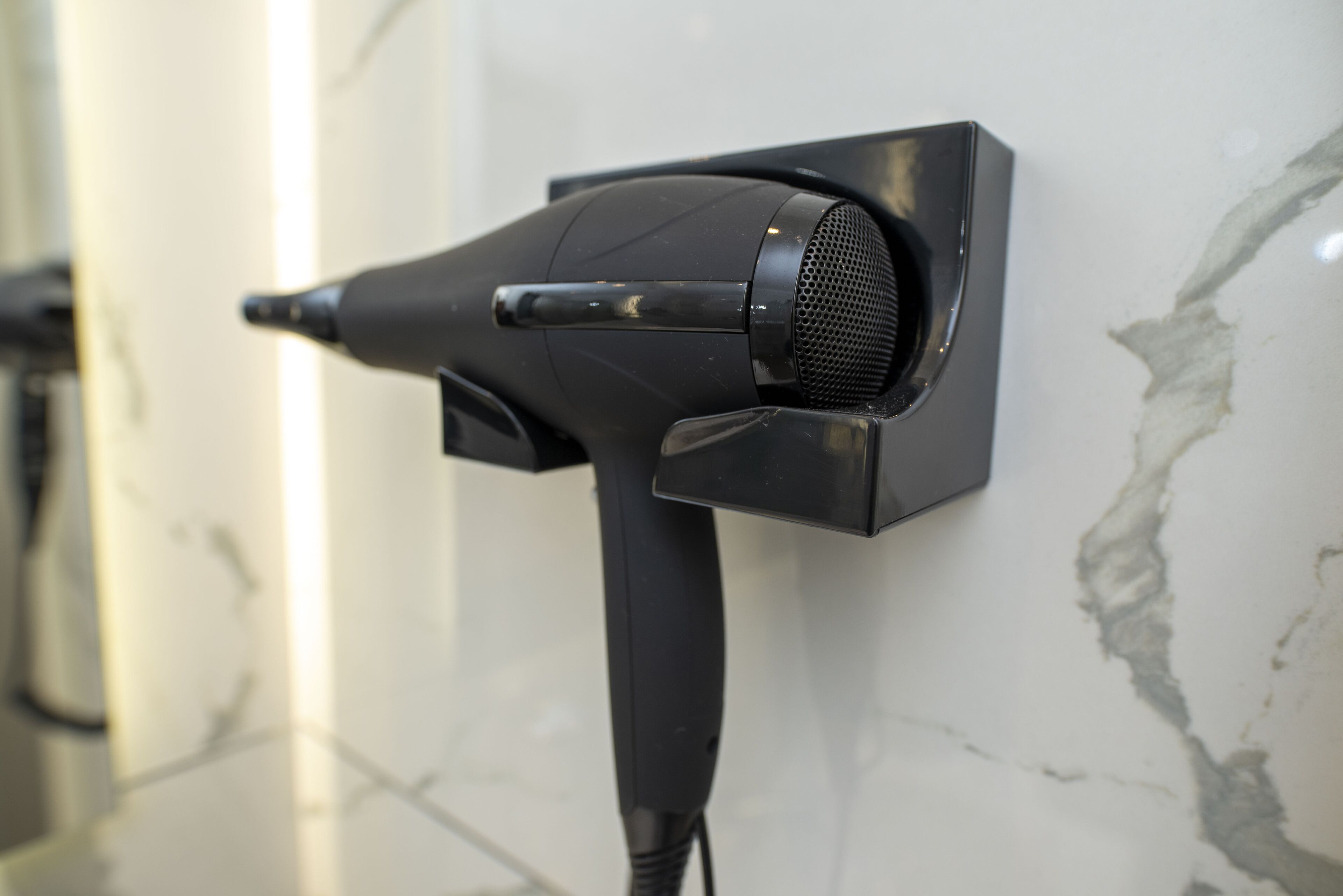 A hair dryer mounted on a wall with a marble surface.