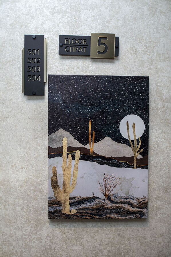 A wall-mounted artwork depicting a desert night scene with cacti and a moon.